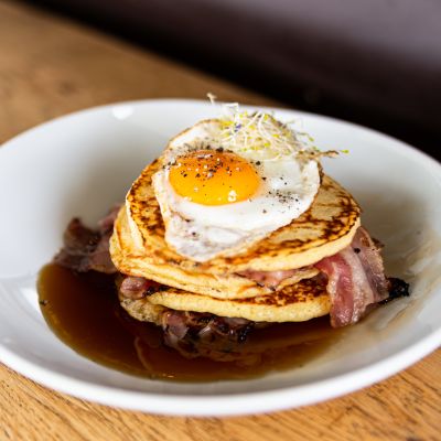 Bacon-Pancakes mit Spiegelei in einem weißen Teller